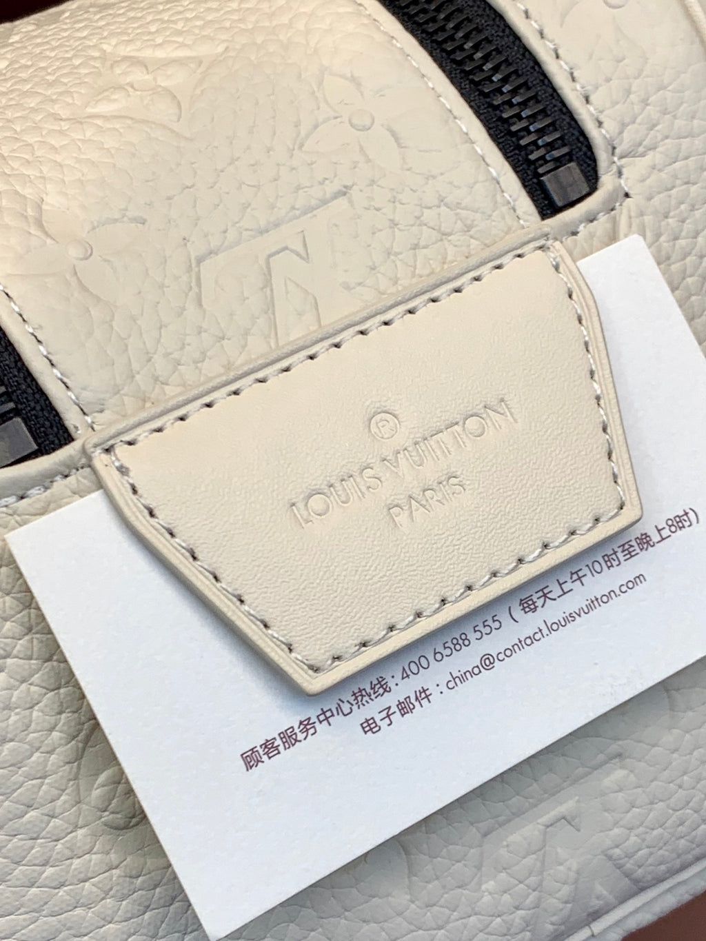 Louis Vuitton Paris tag on white monogram leather pouch with stitched edges