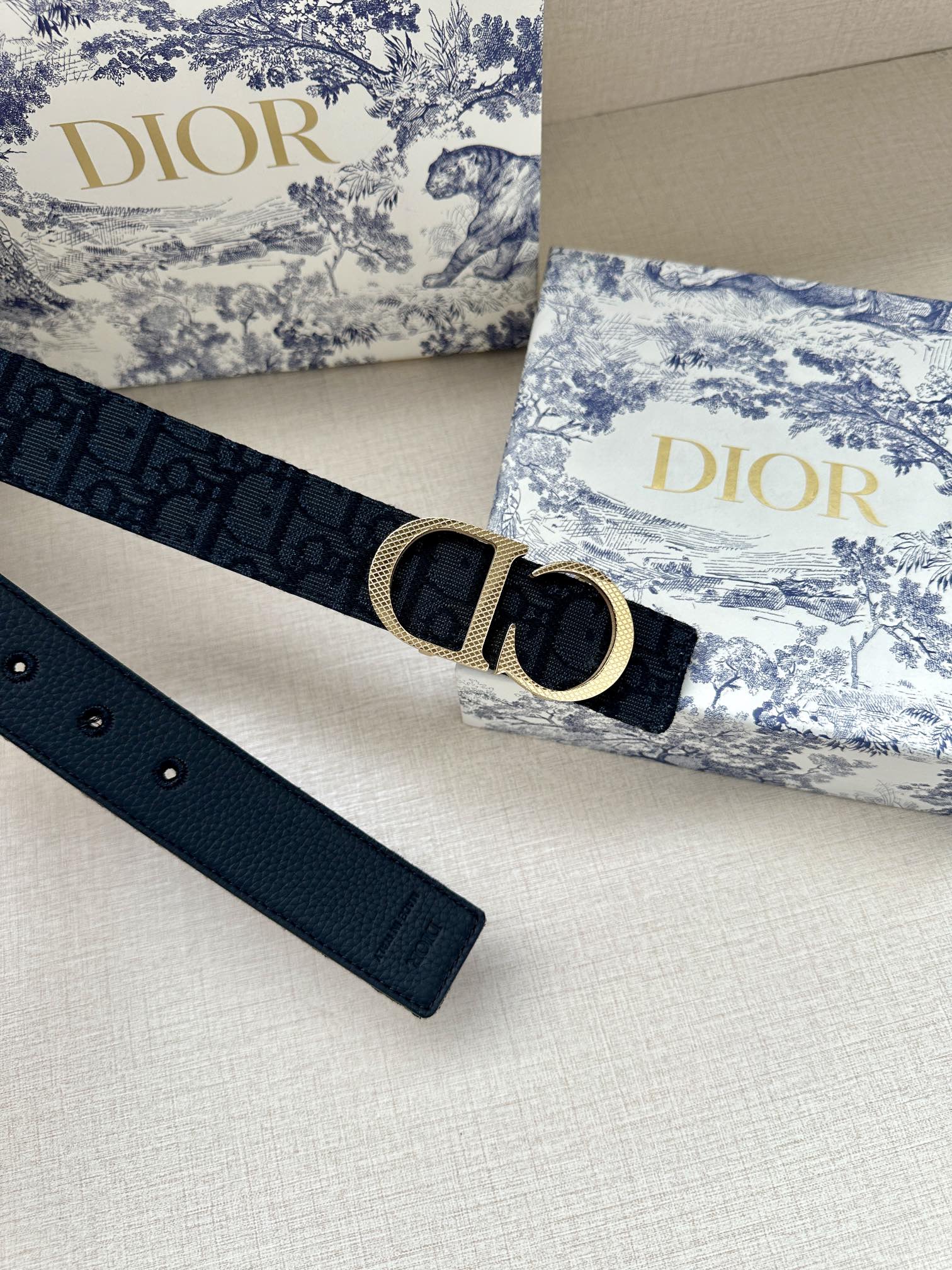 Dior belt with dark navy strap and gold-tone CD buckle with round bar.