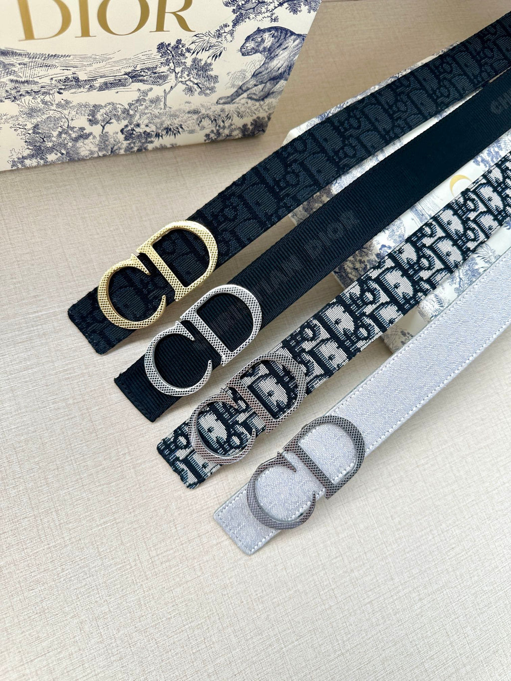 Dior belt set: dark navy and gray straps with silver-tone CD buckles.