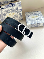 Designer belt: textured navy strap with silver CD buckle and pin holes.