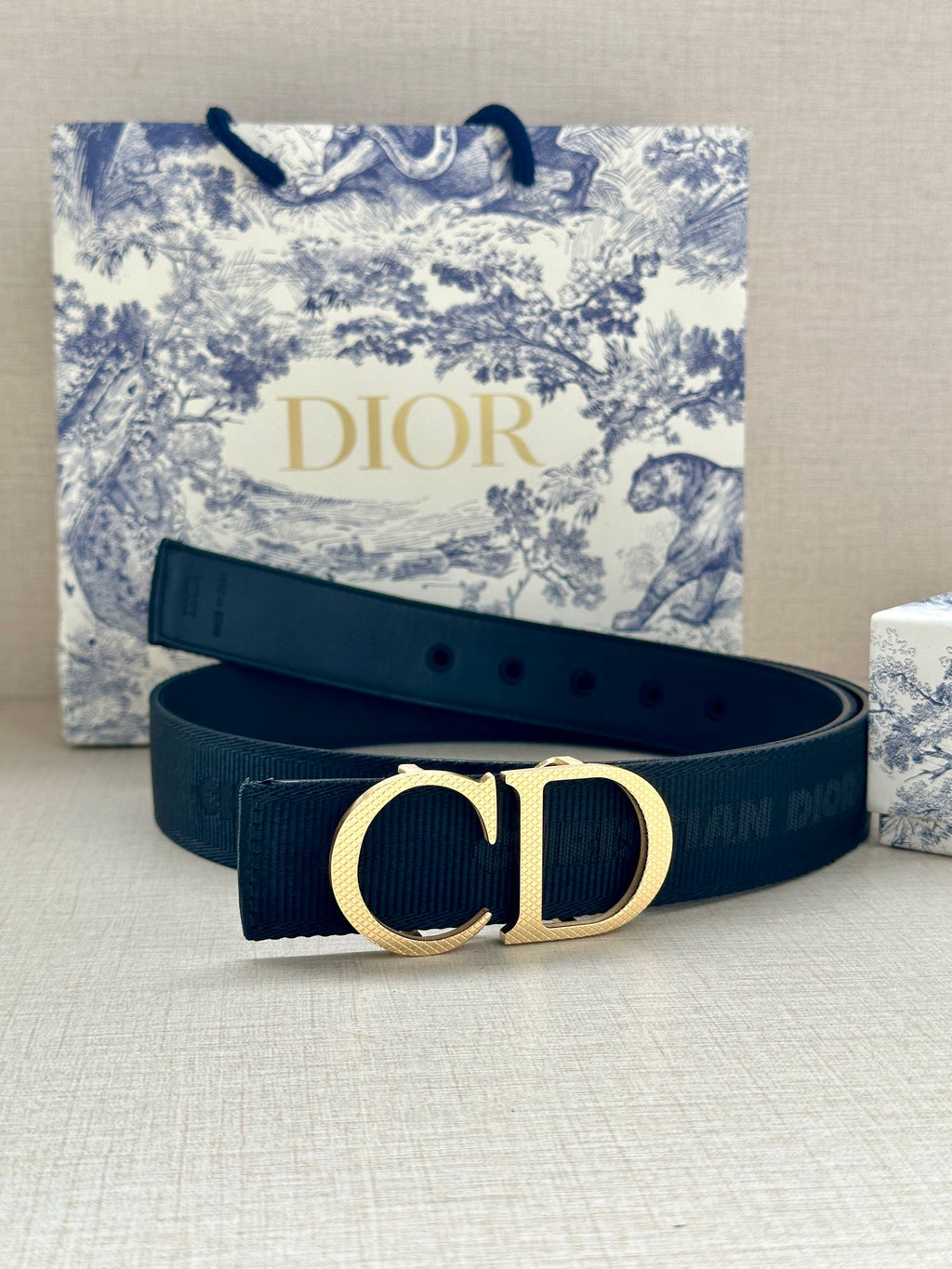Designer belt in dark navy with gold CD buckle, prong side.