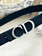 Designer belt close-up: navy strap with silver CD buckle.