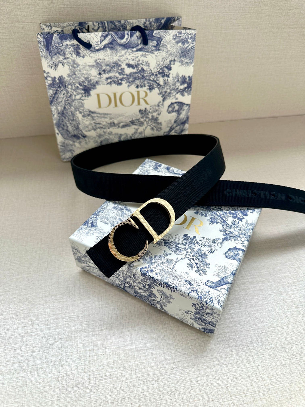 Designer belt with dark navy strap and gold CD buckle.
