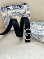 Designer belt with textured navy webbing and silver CD buckle detail.