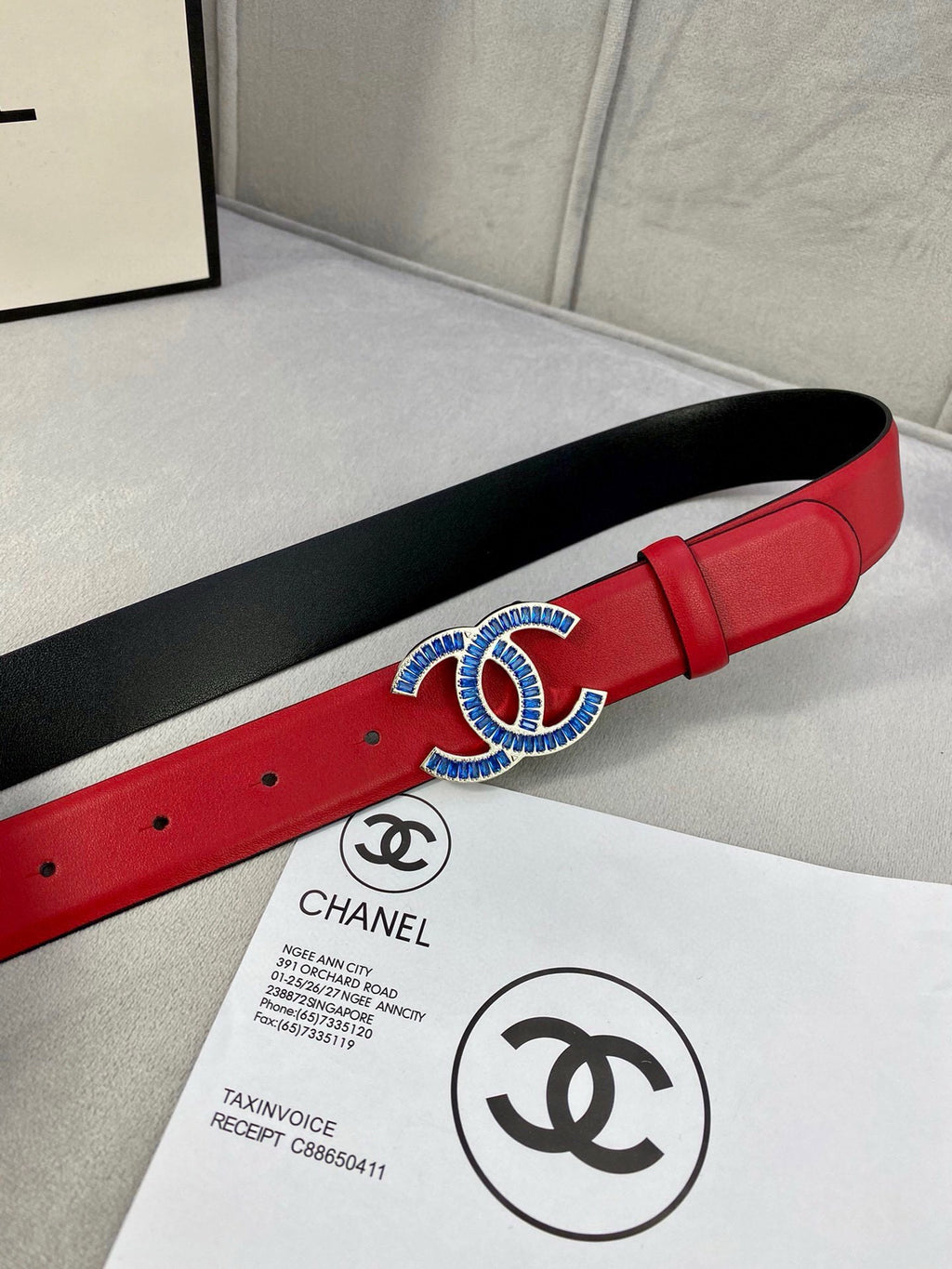Chanel belt red strap with black backing and blue-gold logo buckle on paper
