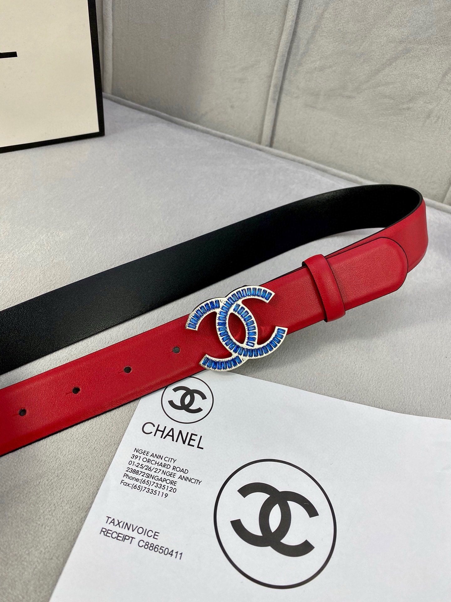 Chanel belt red strap with black backing and blue-gold logo buckle on paper