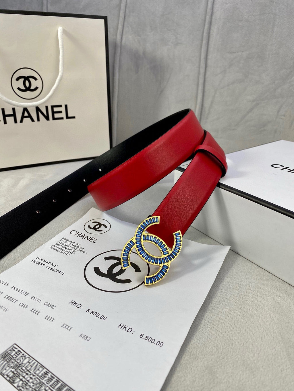 Chanel belt red strap with black backing and blue-gold logo buckle on receipt papers