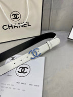 White leather belt with blue CC buckle, resting on a product box.