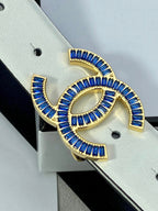Blue enamel CC buckle on white leather belt strap, showing gold-tone edges.