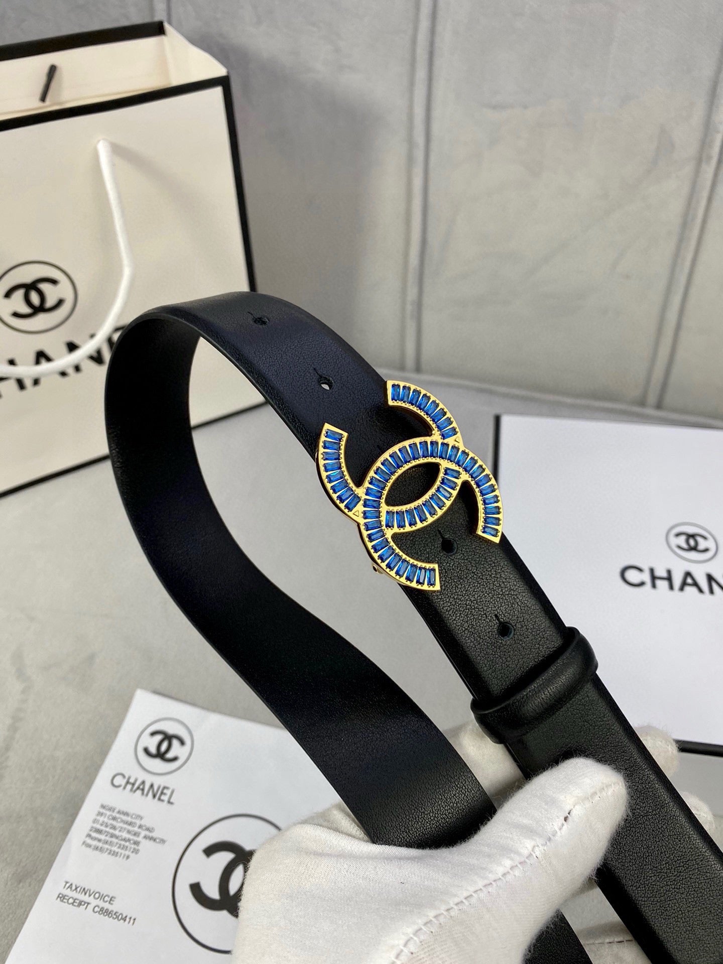 Black Chanel belt with blue jeweled CC buckle, close-up on strap and buckle