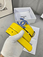 Chanel yellow belt with blue logo buckle and black strap, shown on gloved hand