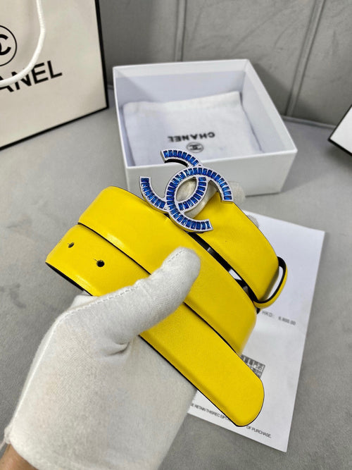 Chanel yellow belt with blue logo buckle and black strap, shown on gloved hand
