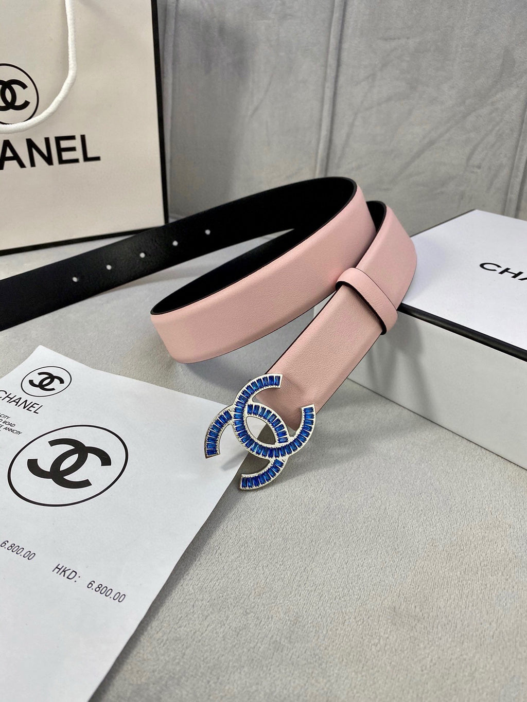 Chanel belt in pink leather with large blue and gold CC-style buckle, black underside.