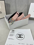Chanel belt in pink leather with blue and gold CC-style buckle, angled on display.