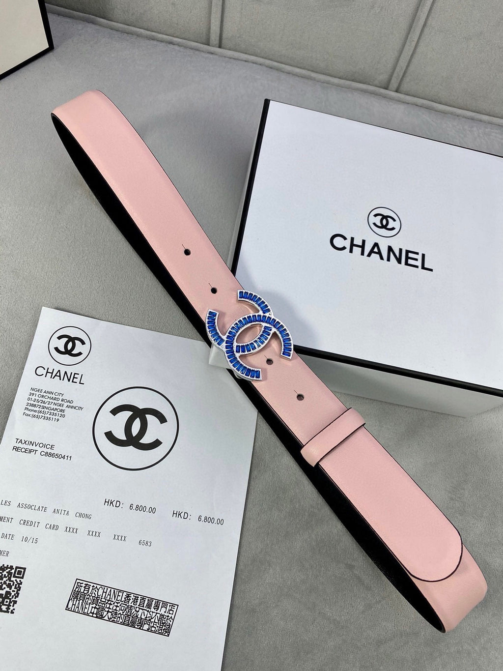 Chanel belt in pink leather with blue and gold CC-style buckle and punched holes.
