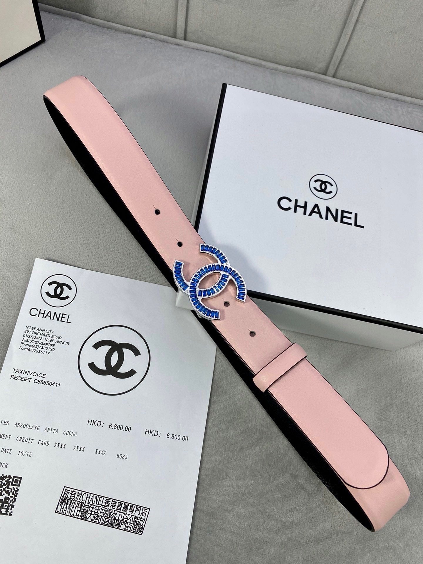 Chanel belt in pink leather with blue and gold CC-style buckle and punched holes.