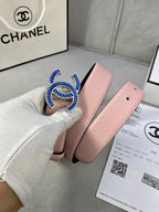 Chanel belt in pink leather held by hand, with blue and gold CC-style buckle.