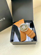 Tan leather belt with round silver-toned logo buckle in a gift box