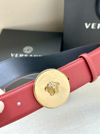 Red leather belt close-up with round gold-tone Medusa buckle