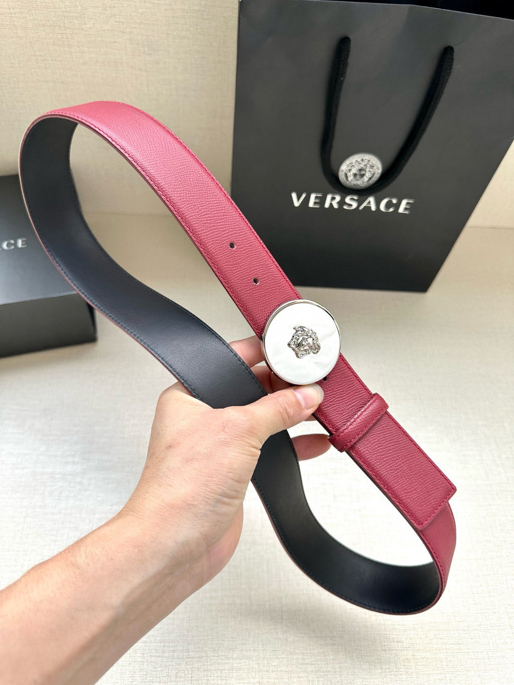 Red leather Versace belt with round Medusa buckle and visible side eyelet holes