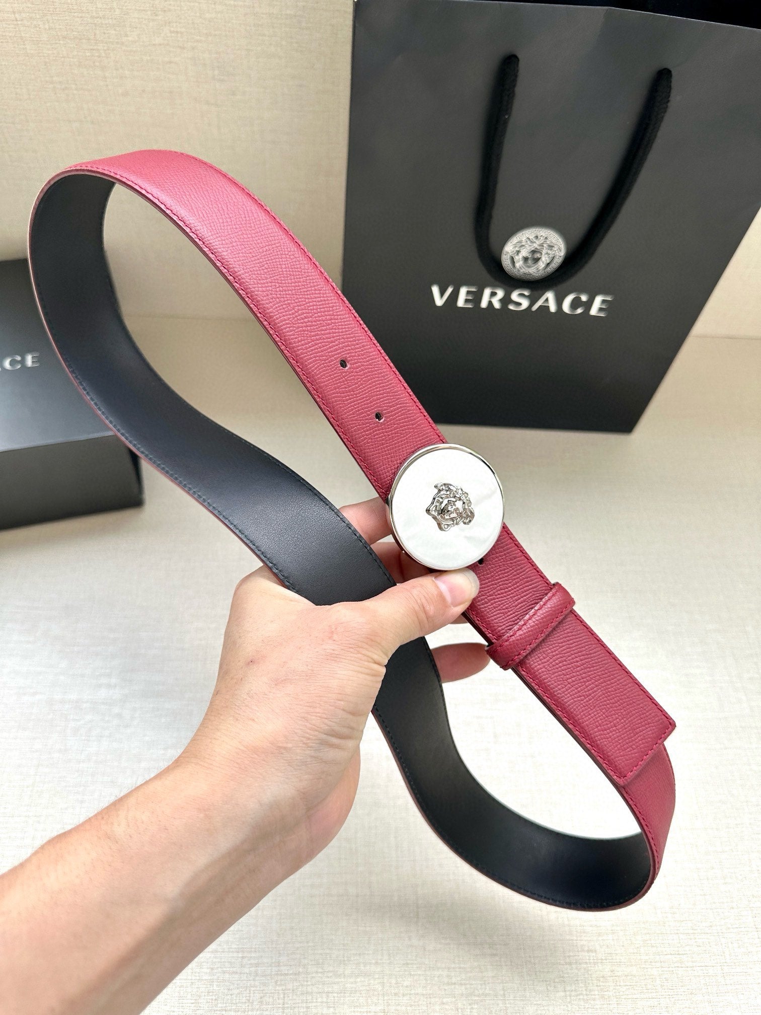 Red leather Versace belt with round Medusa buckle and visible side eyelet holes