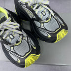 Pair of chunky lace-up sneakers showing gray mesh panels, black soles, and neon yellow accents