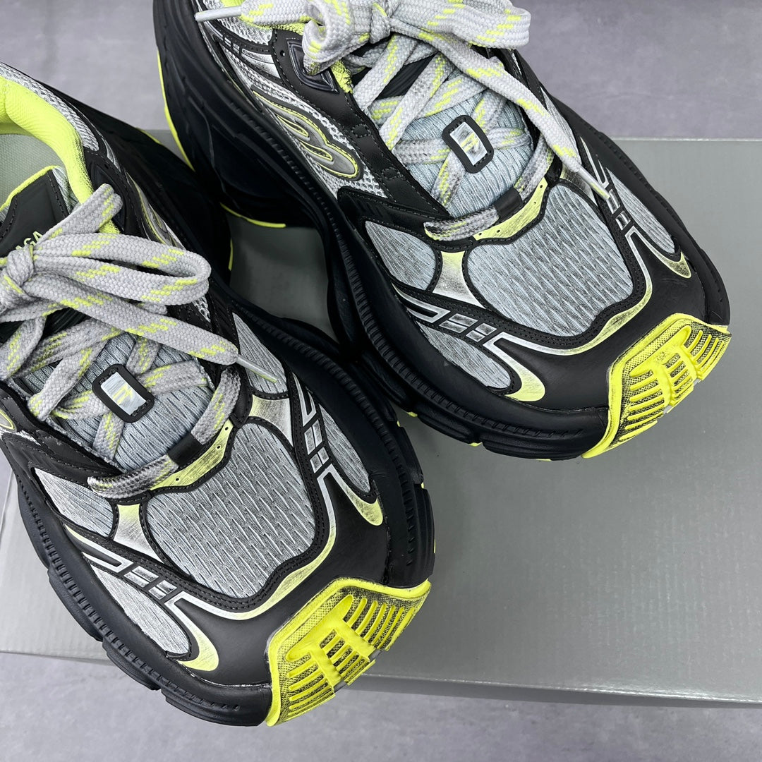 Pair of chunky lace-up sneakers showing gray mesh panels, black soles, and neon yellow accents