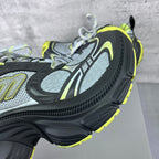 Side view of chunky sneakers with gray mesh, black overlays, and neon yellow edge trim