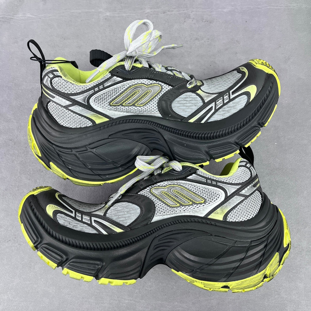 Front view of chunky lace-up sneakers in gray and black with neon yellow highlights