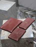 Burgundy leather small bags with gold YSL logo, three clutches on display