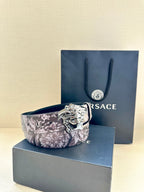 Floral leather belt with silver Medusa buckle, folded with blue packaging