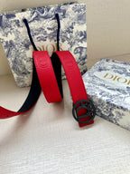 Red leather belt with oval logo buckle and textured strap, punched holes.