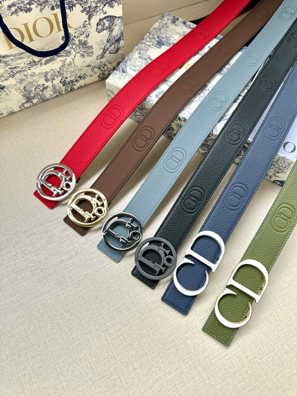 Assorted leather belts with metal buckles: red, tan, blue, gray, green.
