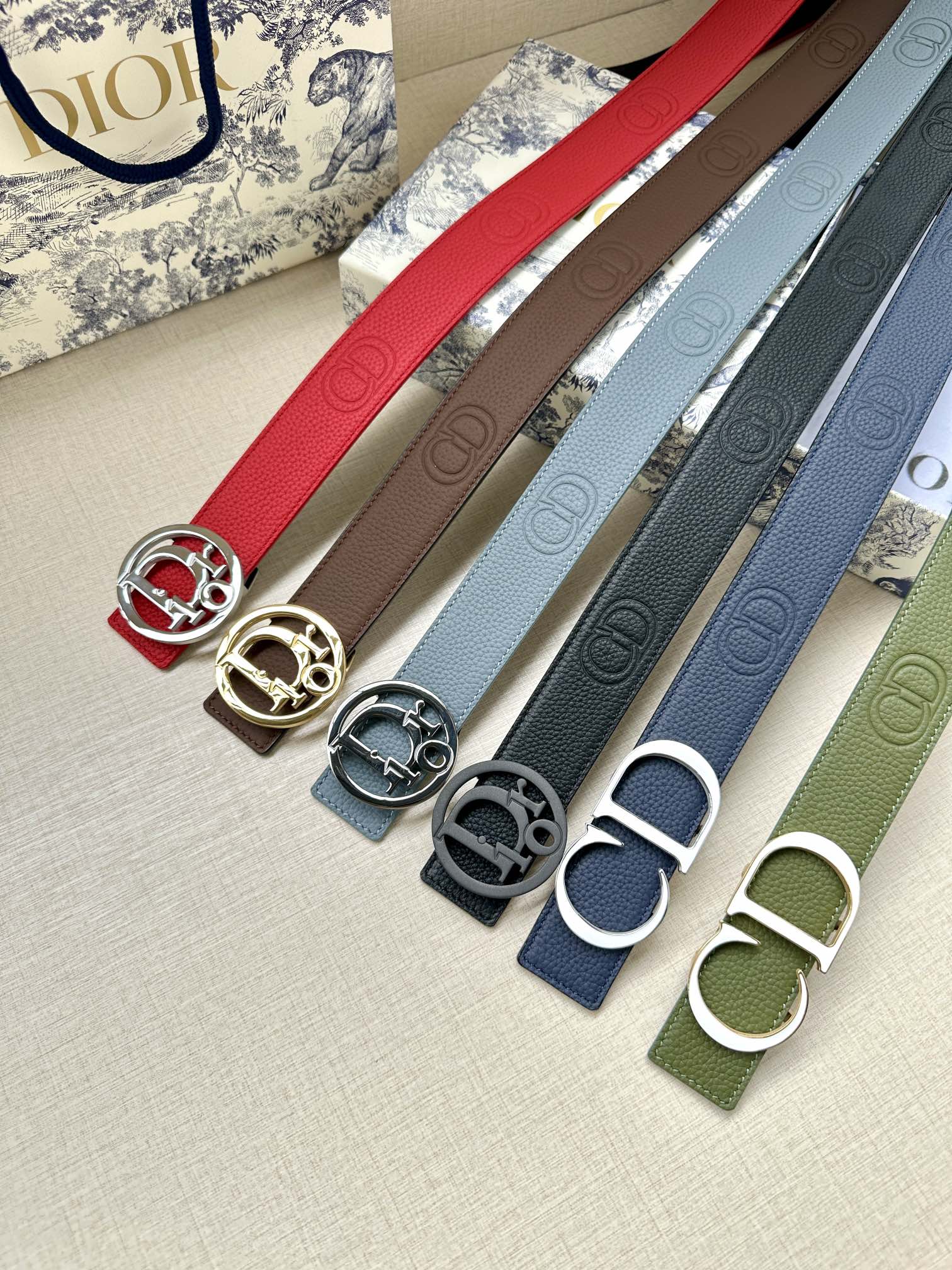 Assorted leather belts with metal buckles: red, tan, blue, gray, green.