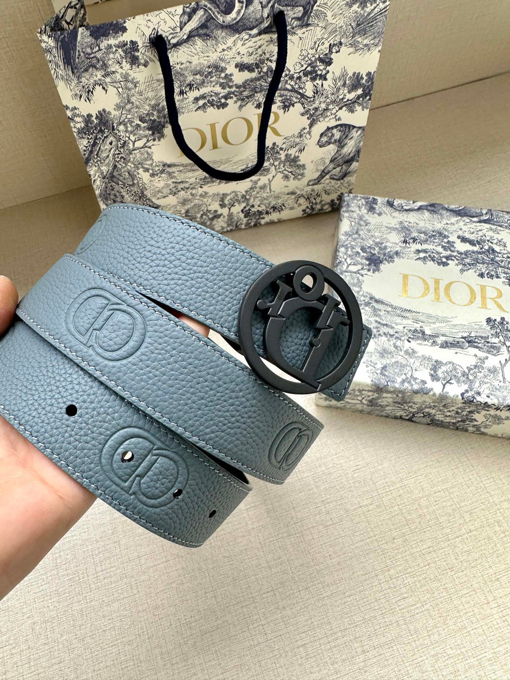 Dior belt close-up: light blue leather with dark CD buckle and stamped logo