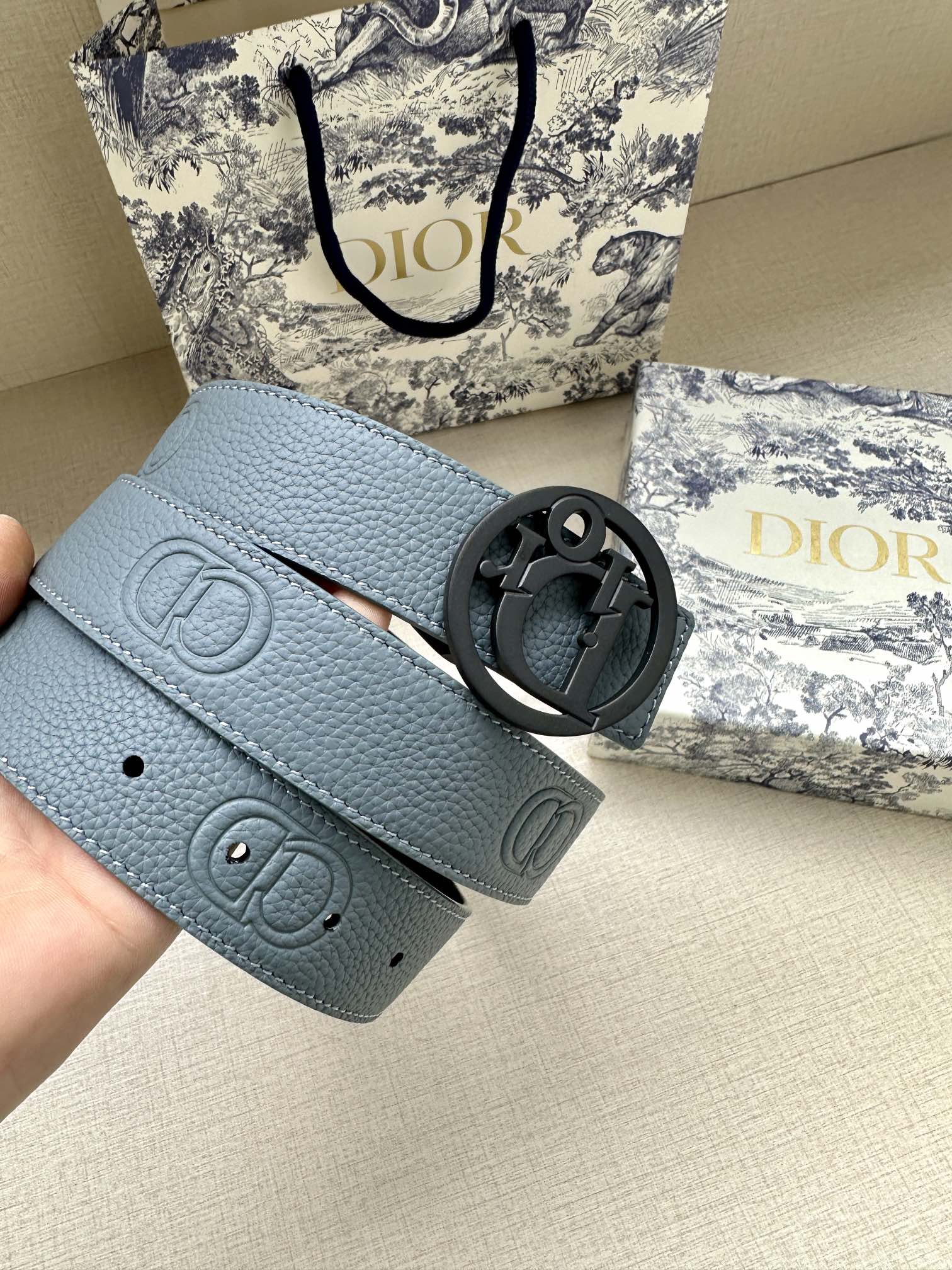 Dior belt close-up: light blue leather with dark CD buckle and stamped logo