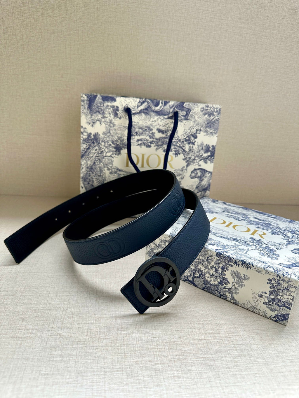 Blue leather belt set with oval logo buckle and overlapping strap pieces.