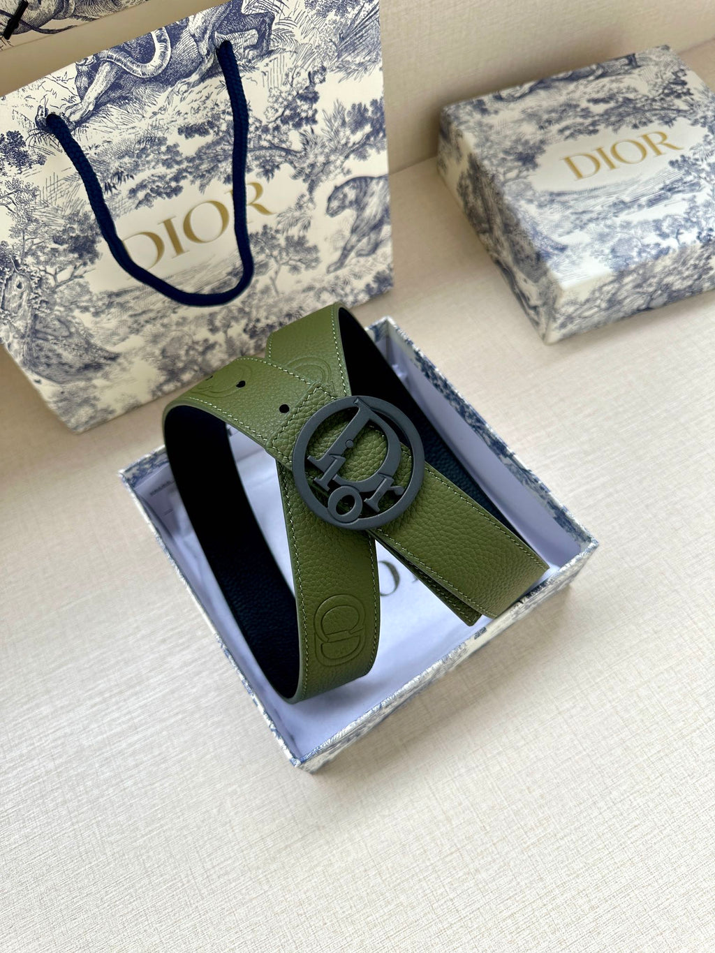 Green leather belt with circular logo buckle on visible strap section