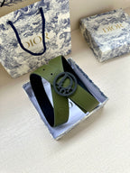 Green leather belt with circular logo buckle on visible strap section