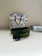 Green leather belt with circular logo buckle laid flat