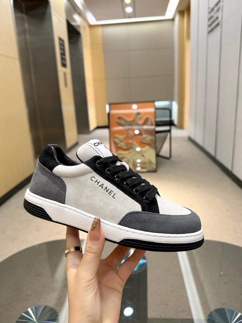 Chanel unisex sneaker in hand, black-and-white low-top with lace-up closure and logo