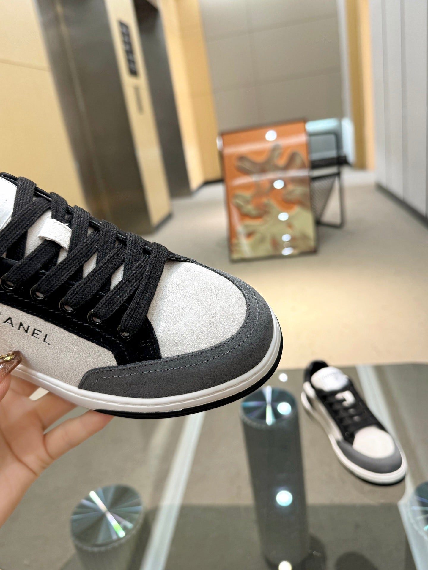 Chanel unisex sneaker close-up, black laces with white toe cap and gray side panel