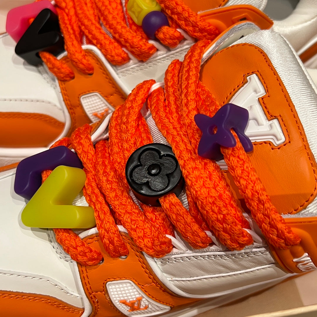 Close-up of orange Louis Vuitton trainer laces with multicolor butterfly charms