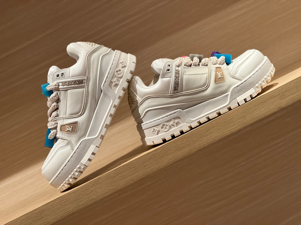 Louis Vuitton trainer shoes, white pair angled on shelf with blue and purple accents