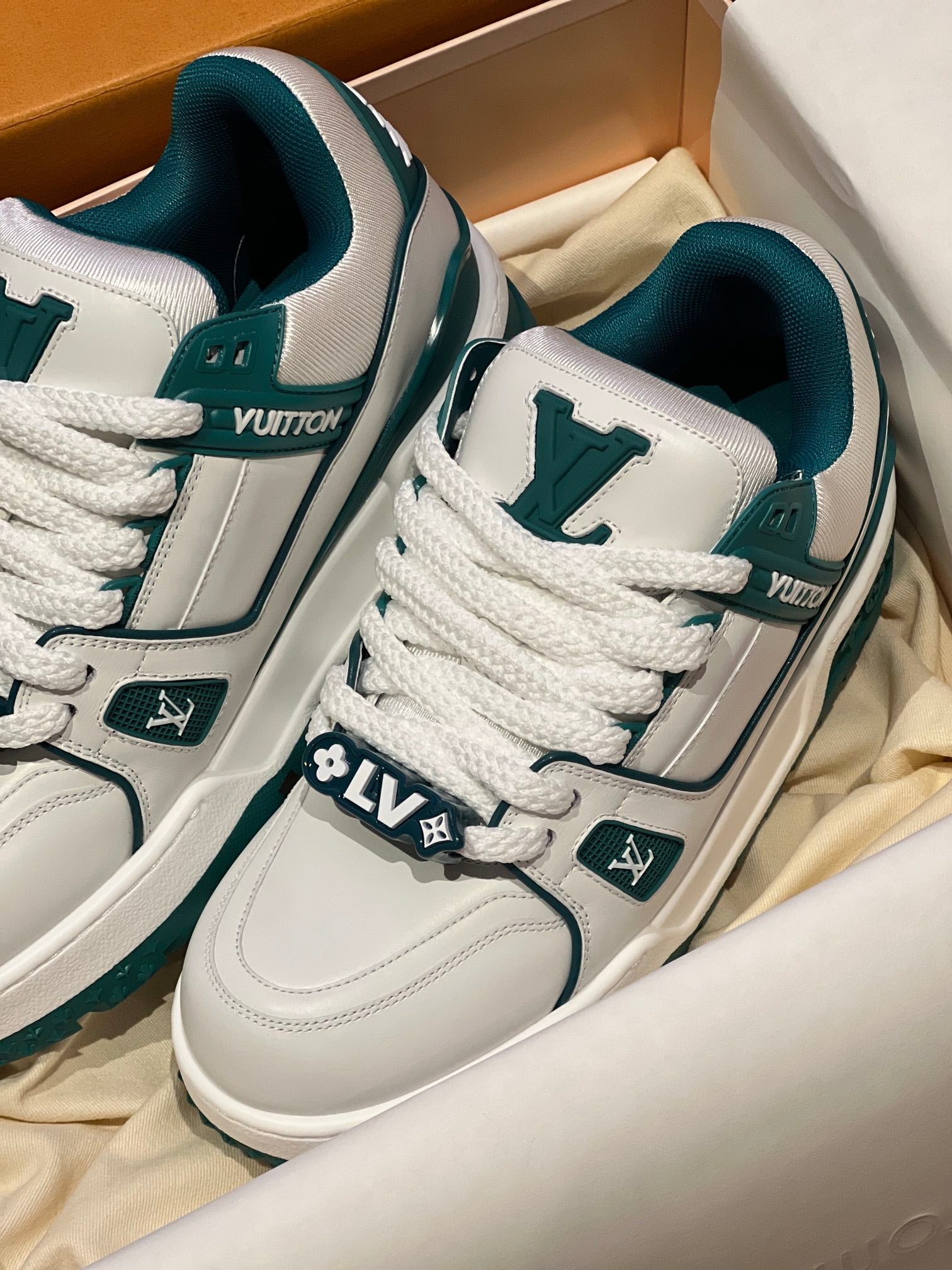 Louis Vuitton low-top sneakers close-up, white leather with teal logo patches