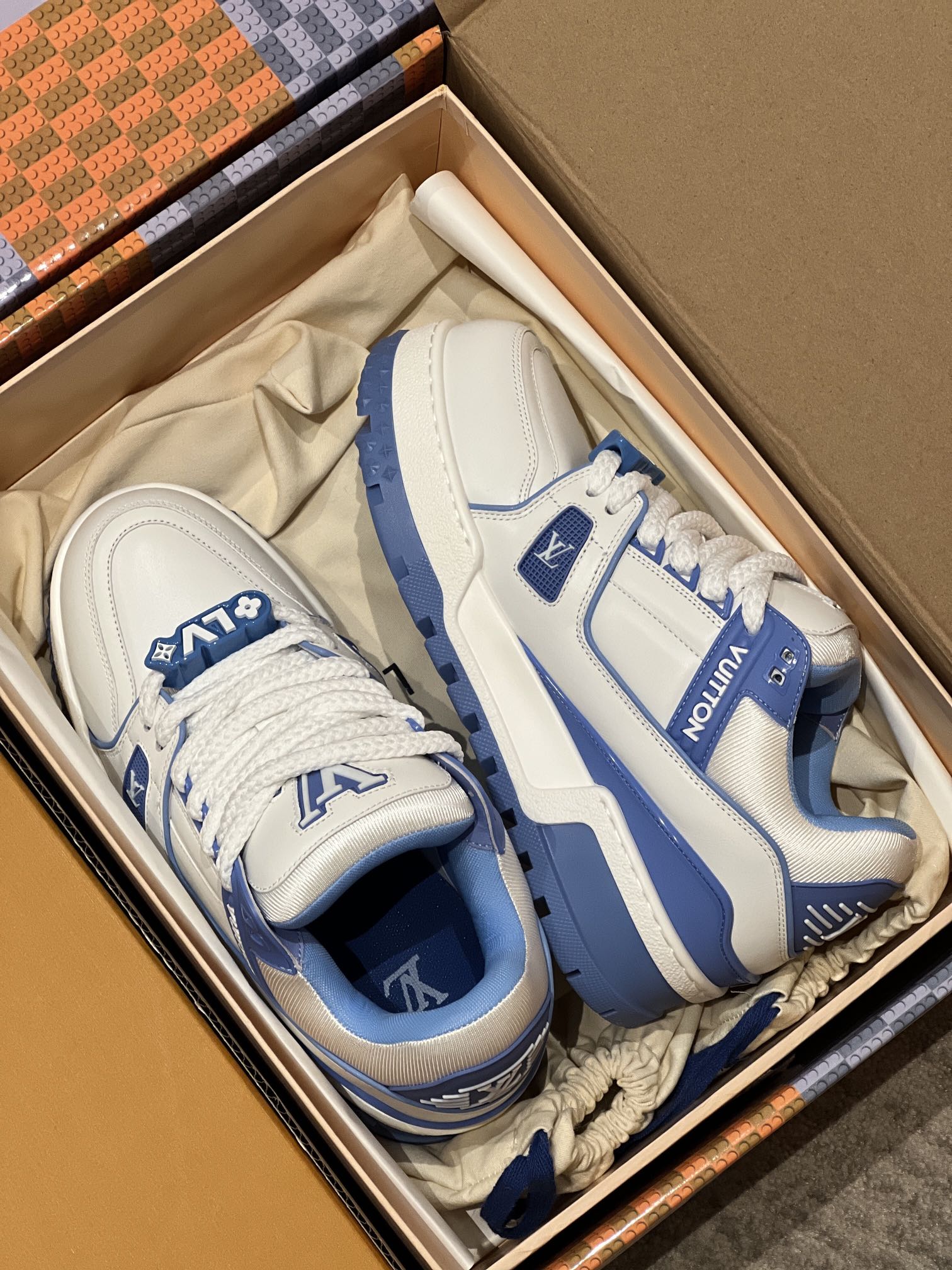 White and blue trainer shoes laid in a box with lace-up fronts
