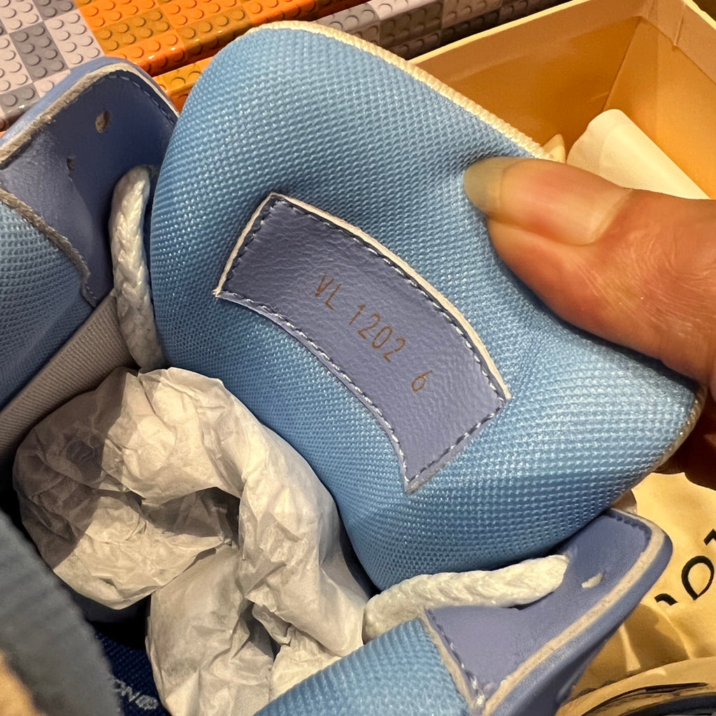 Blue textured trainer shoe tongue label with handwritten-style “LV 2024” text