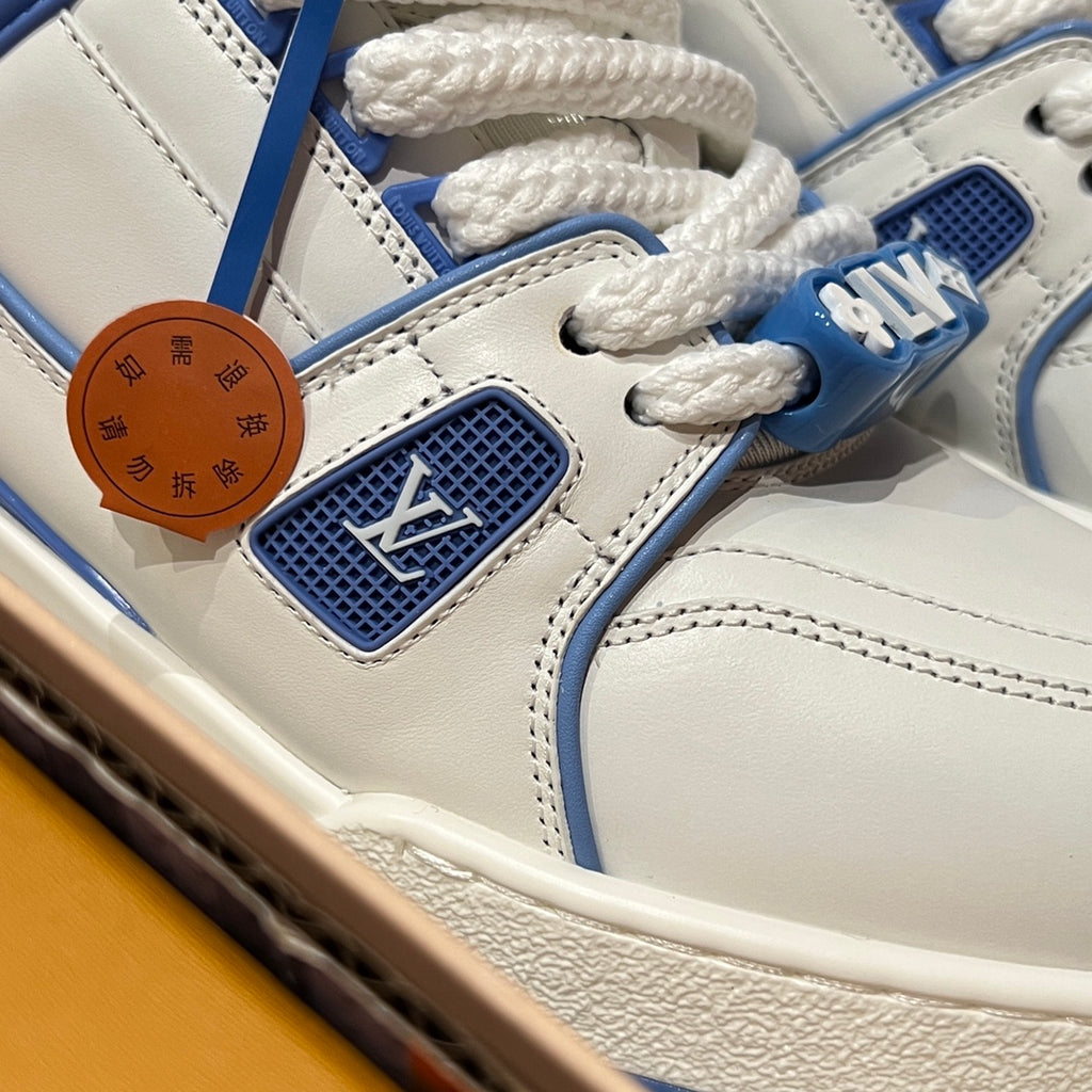 Close-up of white and blue trainer shoe uppers with lace, stitching, and LV patch