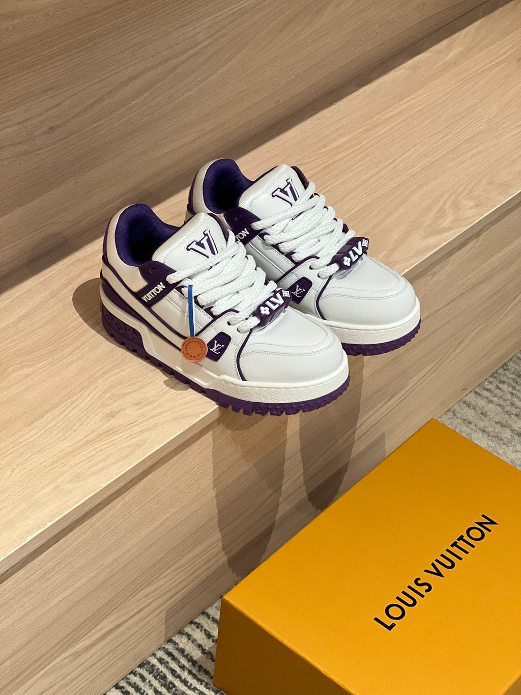 Pair of white and purple low-top sneakers in box, viewed from angled top