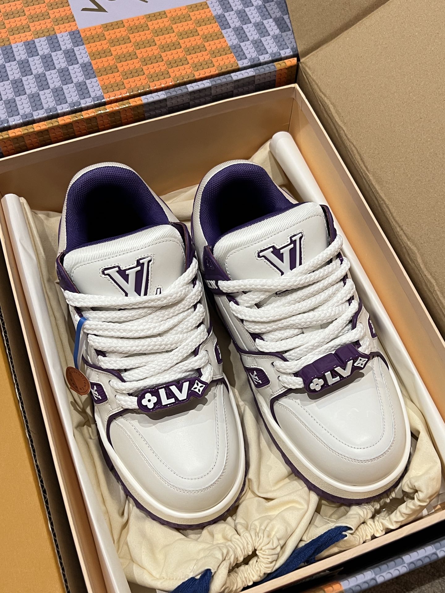 White and purple sneakers with lace-up ties and branded panels in shoe box